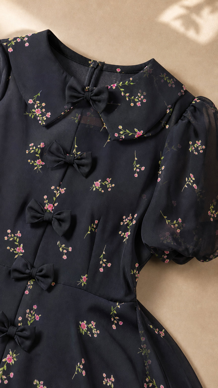 Close-up detail of Peter Pan collar, bow embellishments, and ditsy floral pattern on black dress