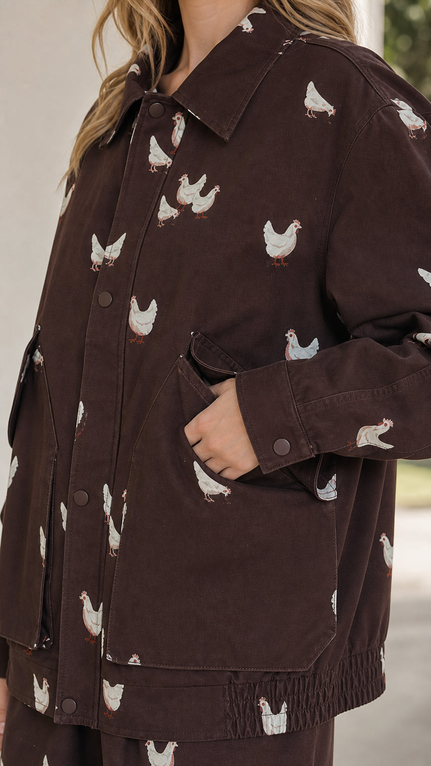 Close-up detail of brown utility jacket showing intricate chicken embroidery and pocket detail