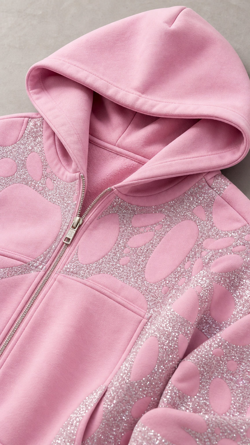 Close-up detail of light pink zip hoodie with hood and glitter pattern