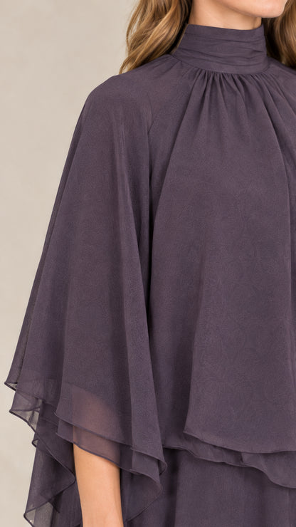 Close-up detail of gathered mock neckline and layered capelet sleeve