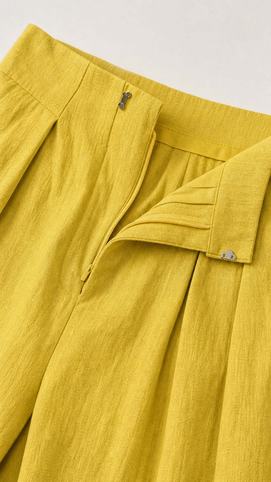 Close-up of yellow jumpsuit waistband and pleat details