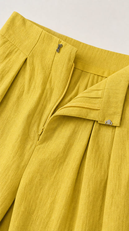 Close-up of yellow jumpsuit waistband and pleat details