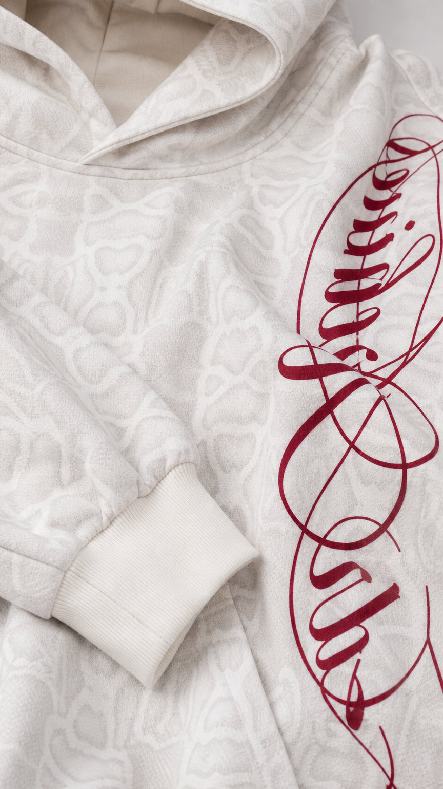 Close-up detail of textured off-white fabric, hood, and red side script print