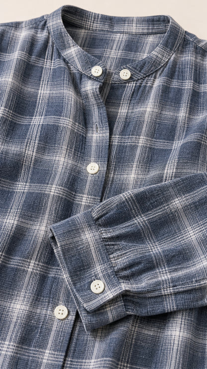 Close-up detail of mandarin band collar, front buttons, and cuff on slate blue plaid woven fabric