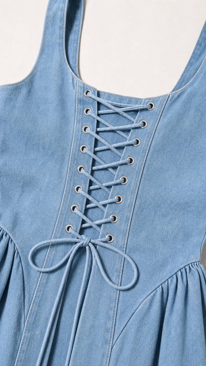 Close-up of the lace-up back grommet detail on light blue denim dress