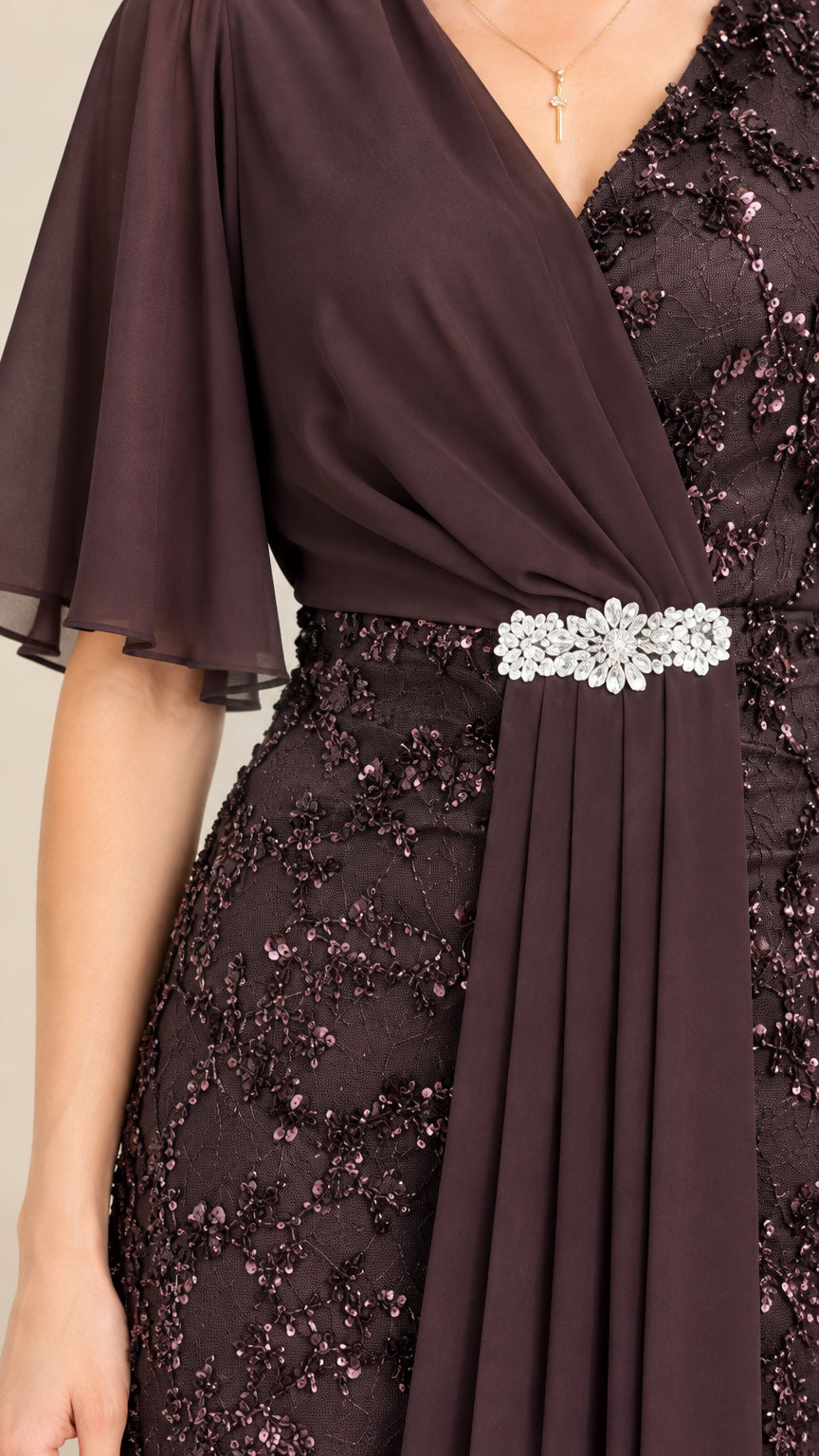 Close-up detail of bodice showing rhinestone waist brooch, chiffon drape, and sequin lace
