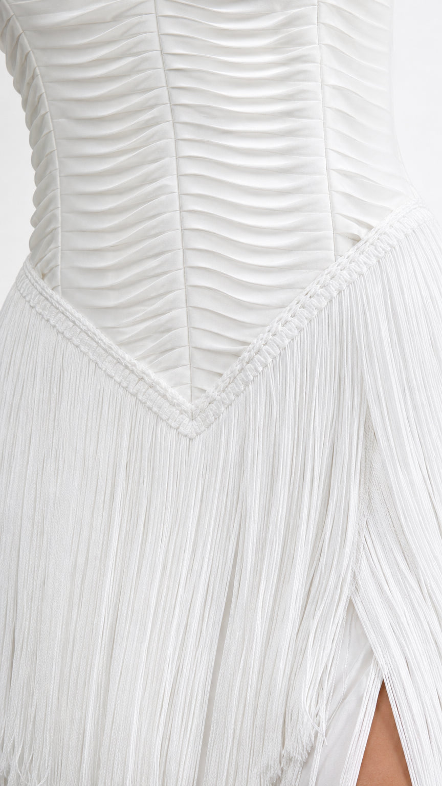 Close-up detail of textured horizontal pleats and fringe waist seam