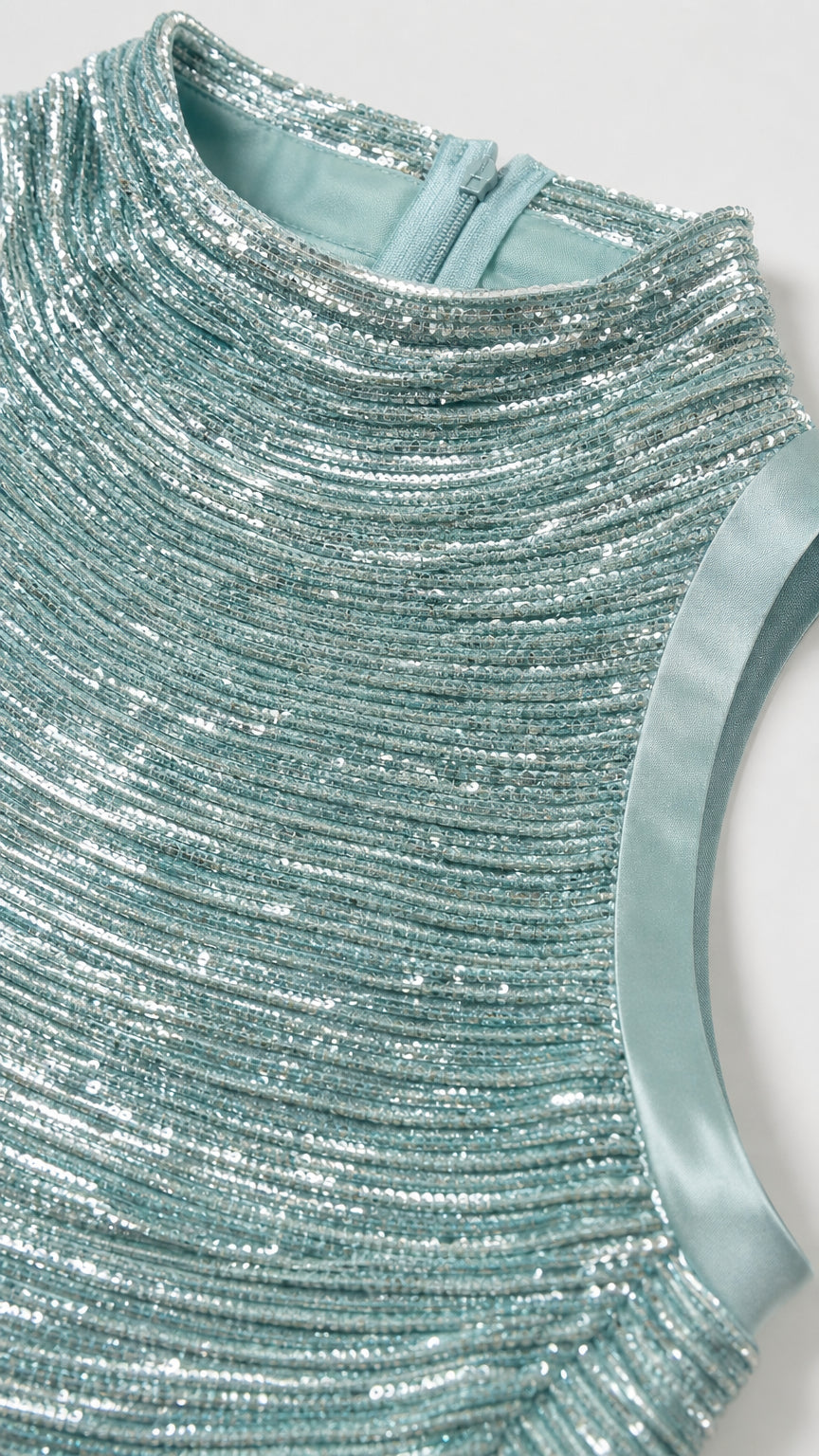Close-up detail of mint green textured sequin fabric and high mock neckline with back zipper