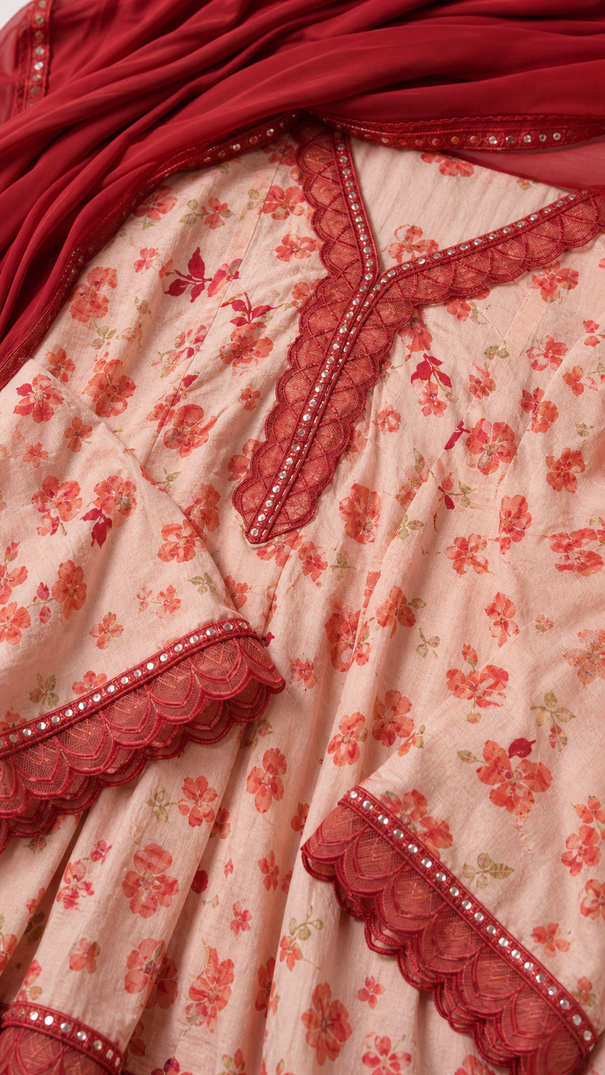 Close up of embroidered neckline and scalloped sleeves on floral tunic