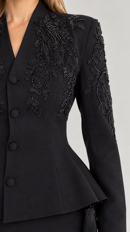 Close-up detail of black beaded floral embroidery and buttoned peplum waist