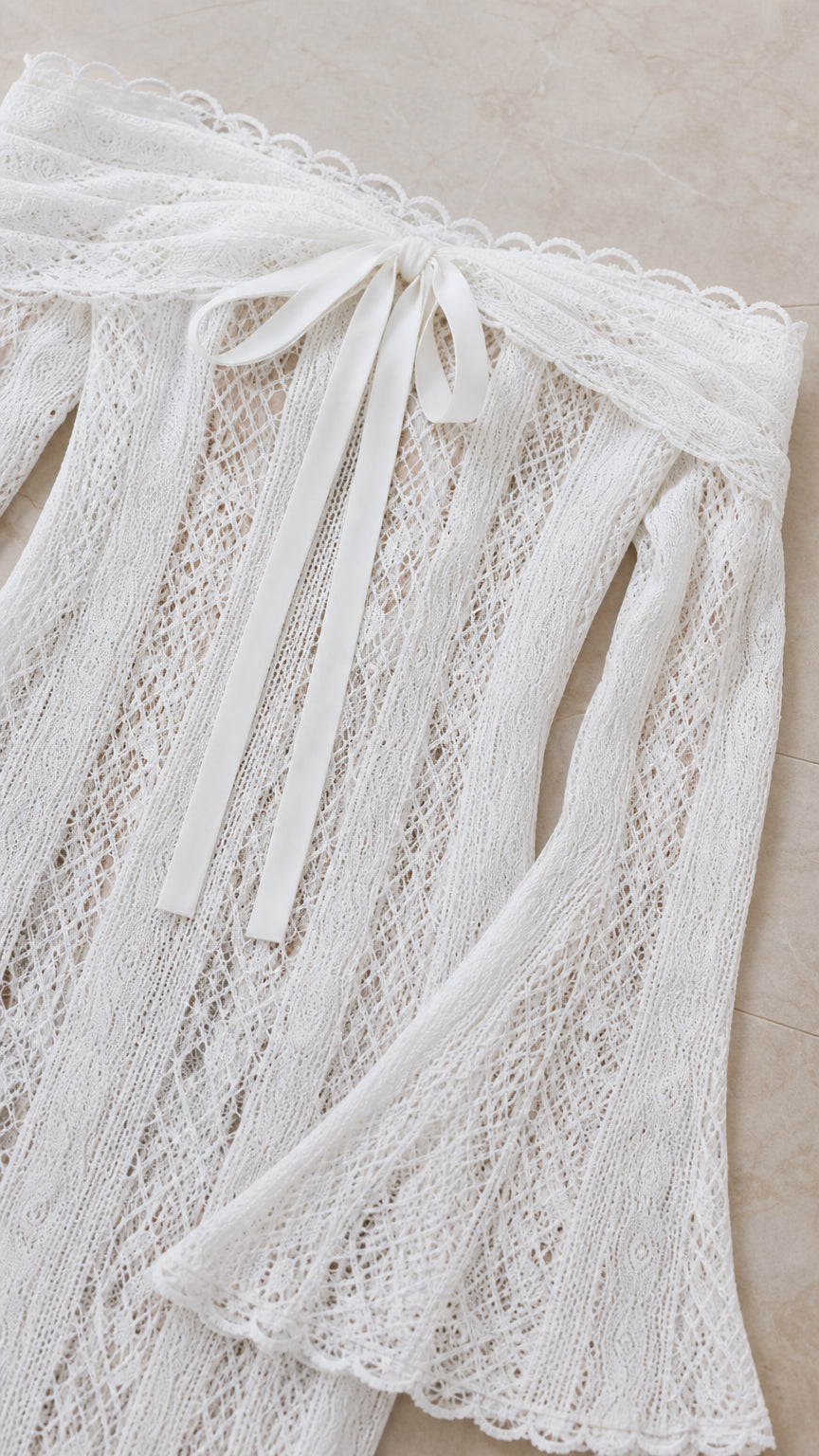 Close-up detail of white lace neckline, bow tie, and delicate scalloped trim