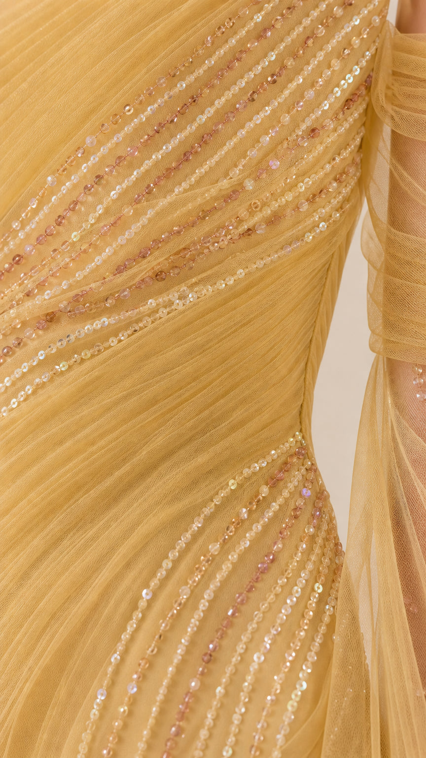 Close-up detail of delicate sequin lines and ruched tulle mesh fabric on gold gown