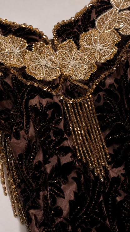 Close-up detail of ornate floral embroidery and beaded tassel fringe on neckline