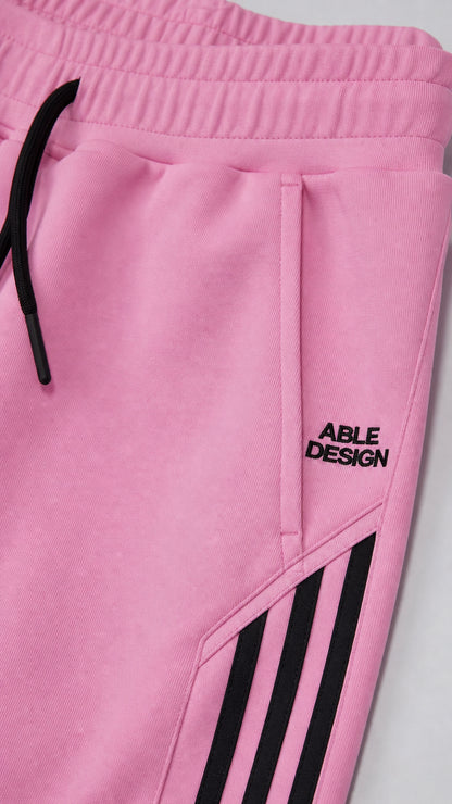 Close up of pink sweatpants waistband, drawstring, pocket, and side stripes