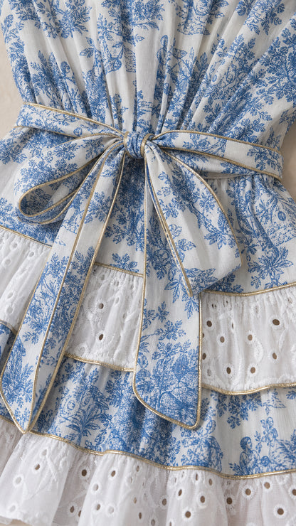 Close up of waist tie and tiered eyelet hem on blue floral dress
