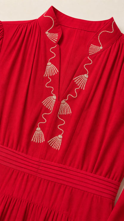 Close up view of gold-tone embroidery along V-neckline on red dress