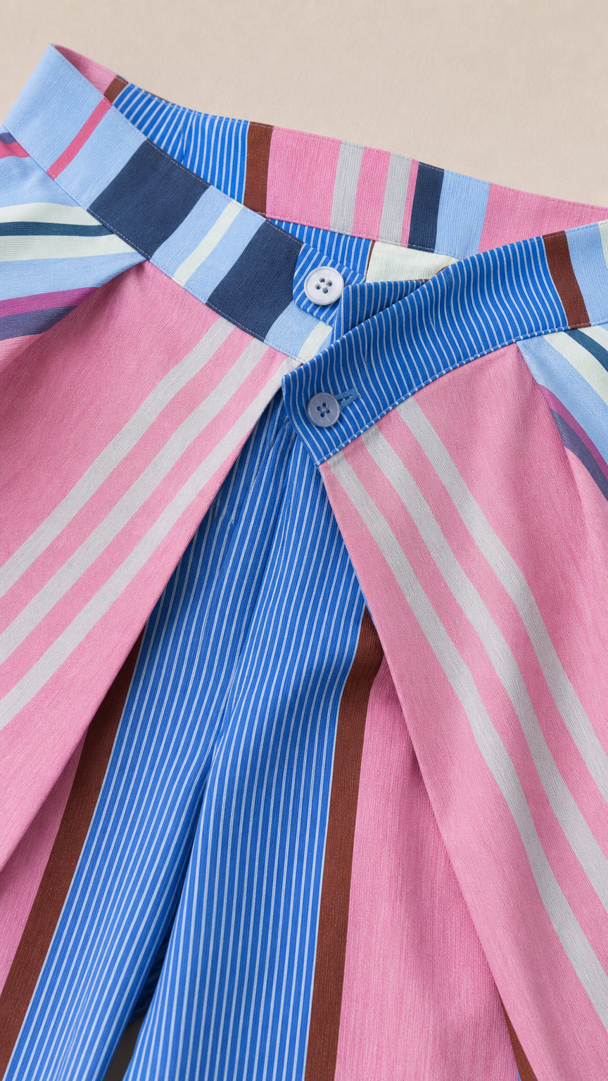 Close-up detail of waistband and button closure on striped trousers