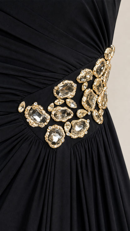 Close-up of gathered fabric and gemstone embellishment on black dress