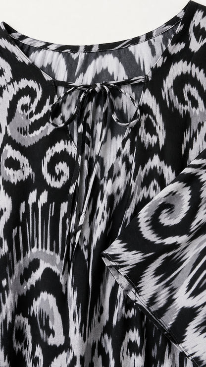Close-up detail of front tie-neck closure and ikat pattern on black kaftan dress