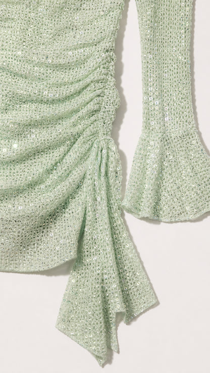 Close-up detail of sage green shimmer fabric, ruching, and flared cuff