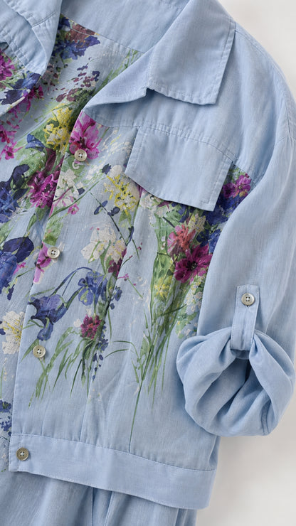 Close-up detail of sky blue jacket fabric, chest pockets, buttons, and roll-tab sleeve