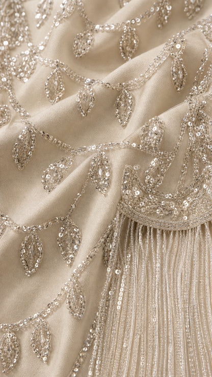 Close-up detail of champagne embroidered beadwork, sequins, and fringe tassels