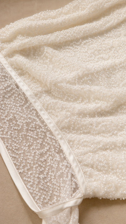 Close-up detail of textured white sequin fabric and trim