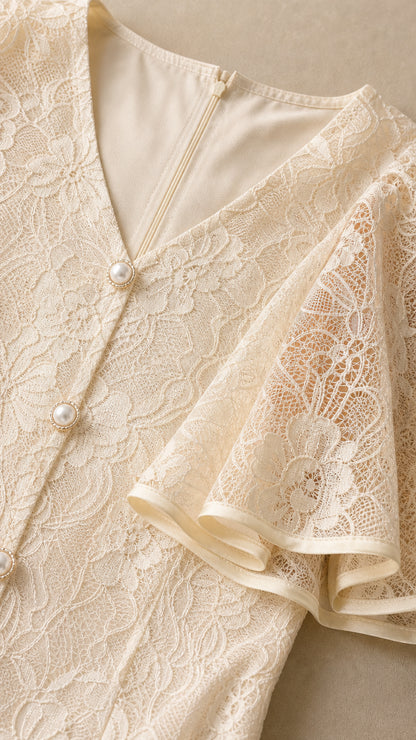Close-up detail of V-neckline, lace texture, and pearl buttons on Ivory dress