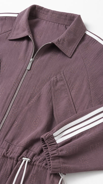 Close-up detail of textured fabric, collar, chest pocket, and zipper on mauve track jumpsuit