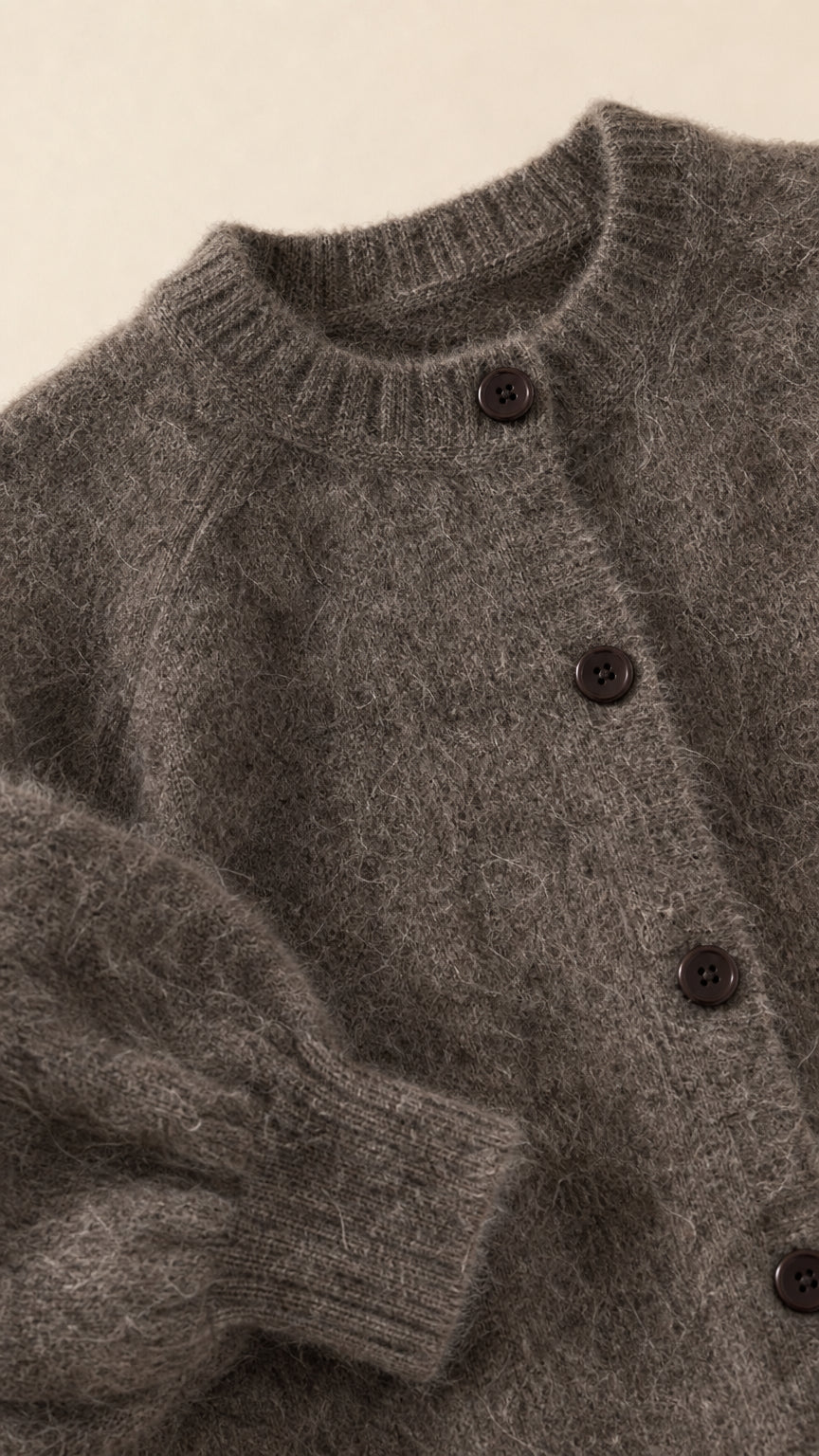 Close-up detail of charcoal grey fuzzy cardigan neckline, buttons, and texture