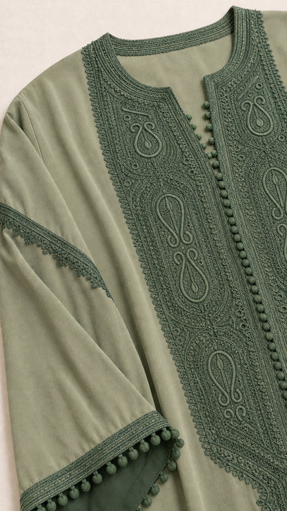 Close-up detail of green embroidery, front placket, and pom-pom sleeve trim