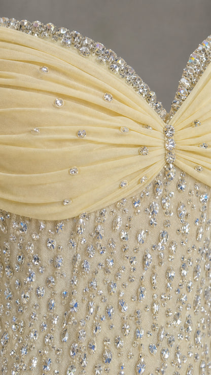 Close-up detail of crystal beadwork and draped neckline on yellow gown