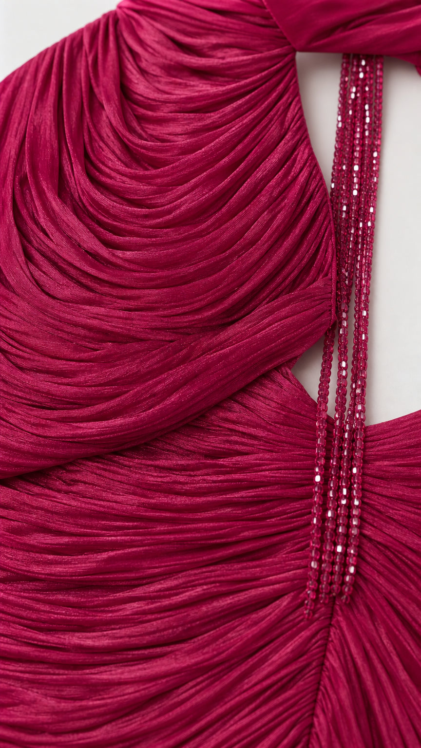 Close-up detail of textured micro-pleating and beaded tassel on magenta dress