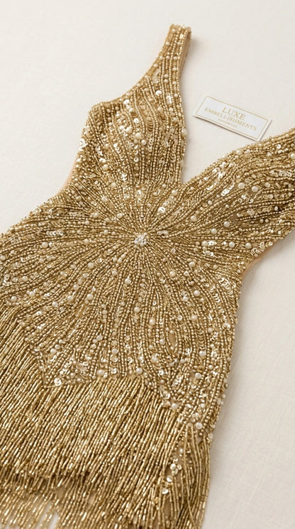 Close-up detail of intricate beadwork and fringe on the gold dress