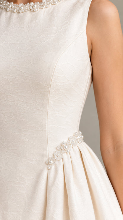 Close-up detail of textured fabric and delicate pearl embellishments on bodice and waist