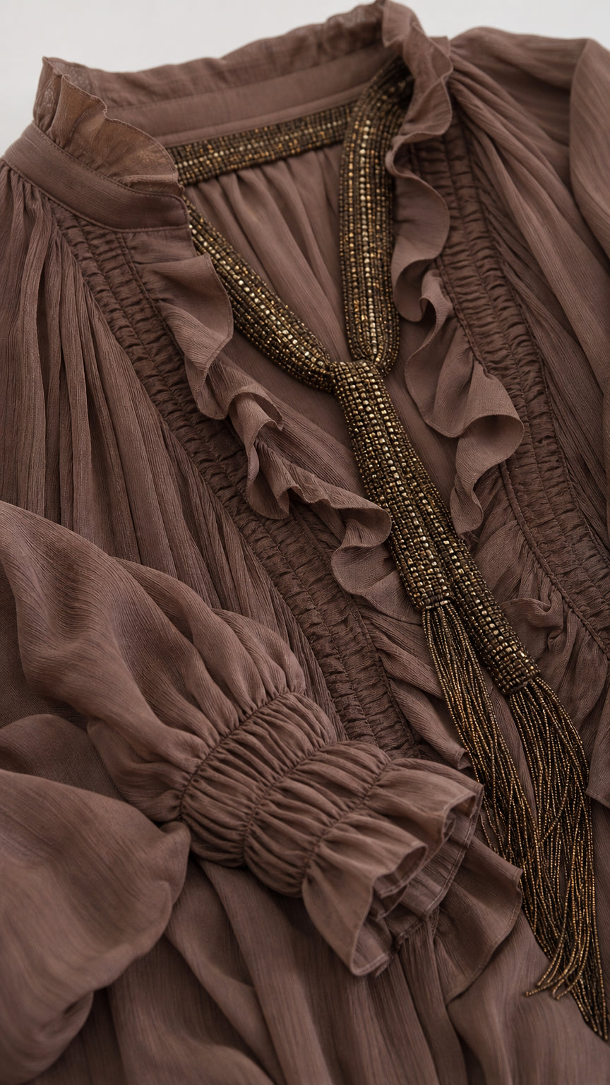 Close-up detail of ruffle neckline, textured fabric, and beaded neck ties on boho blouse