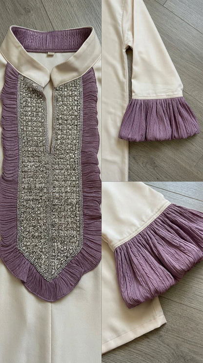 Close-up detail of the embroidered bib neckline and pleated sleeve cuff trim