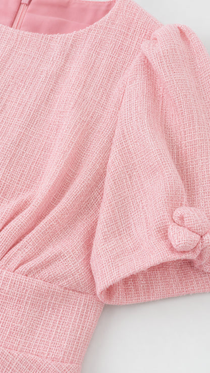 Close-up detail of light pink textured woven fabric and short puff sleeve knot cuff