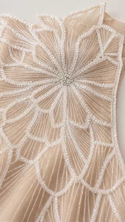 Close-up detail of champagne beaded leaf and floral embroidery on tulle fabric
