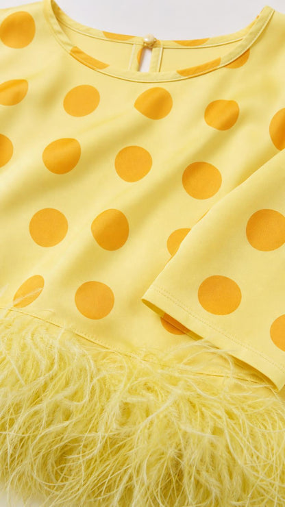 Close up of yellow polka dot fabric and feather hem