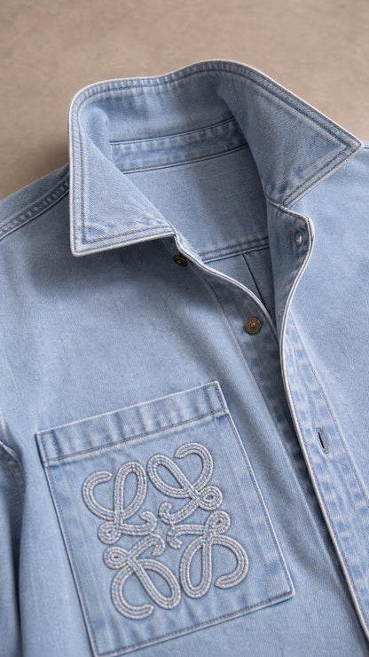 Close-up of light blue denim shirt collar and embroidered chest pocket