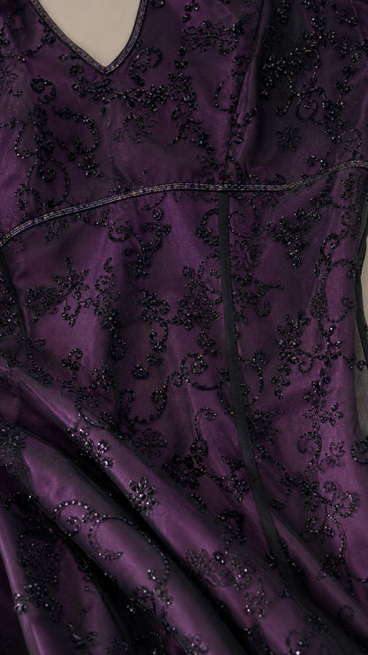 Close-up detail of delicate floral embroidery and beaded texture on deep purple fabric