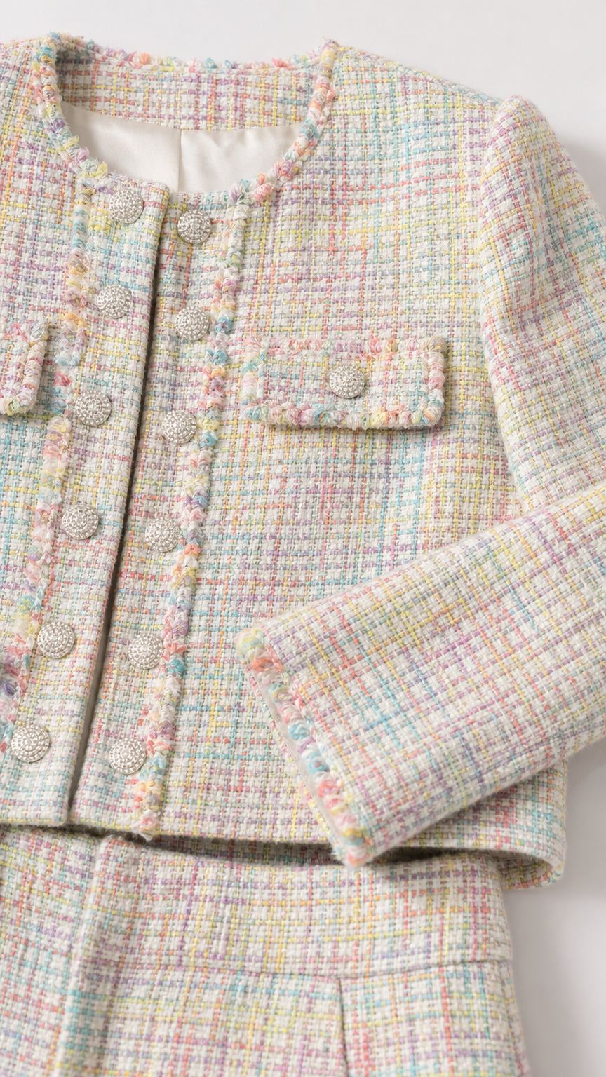 Close-up detail of multi-color tweed fabric and ornate buttons