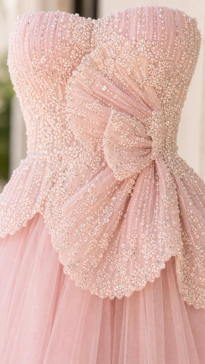 Close-up of blush pink beaded bodice with bow detail and scalloped peplum