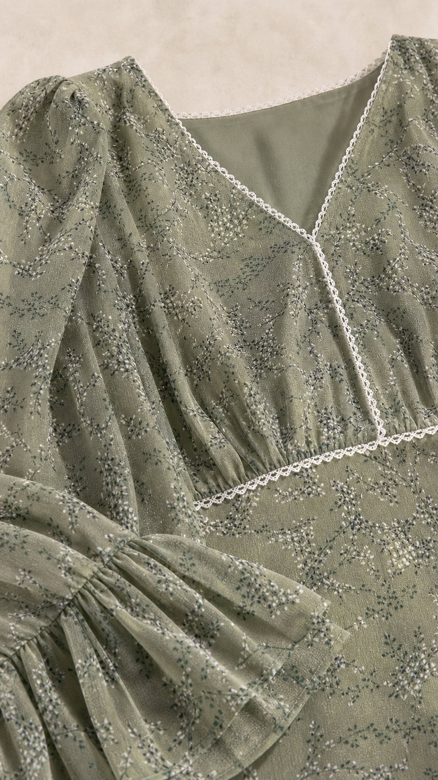 Close-up of sage green floral print fabric with lace V-neckline and ruffled sleeve detail