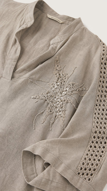 Close-up of taupe top showing V-neckline and sequin starburst embroidery
