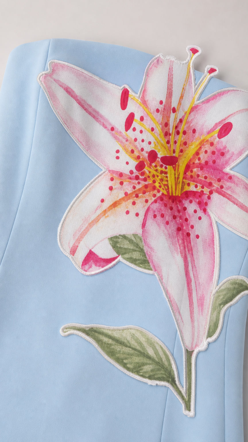 Close-up detail of pink and yellow lily floral print on light blue fabric