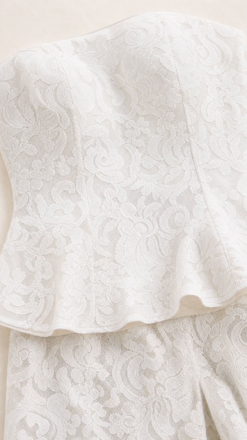Close-up detail of white floral lace texture and peplum hem