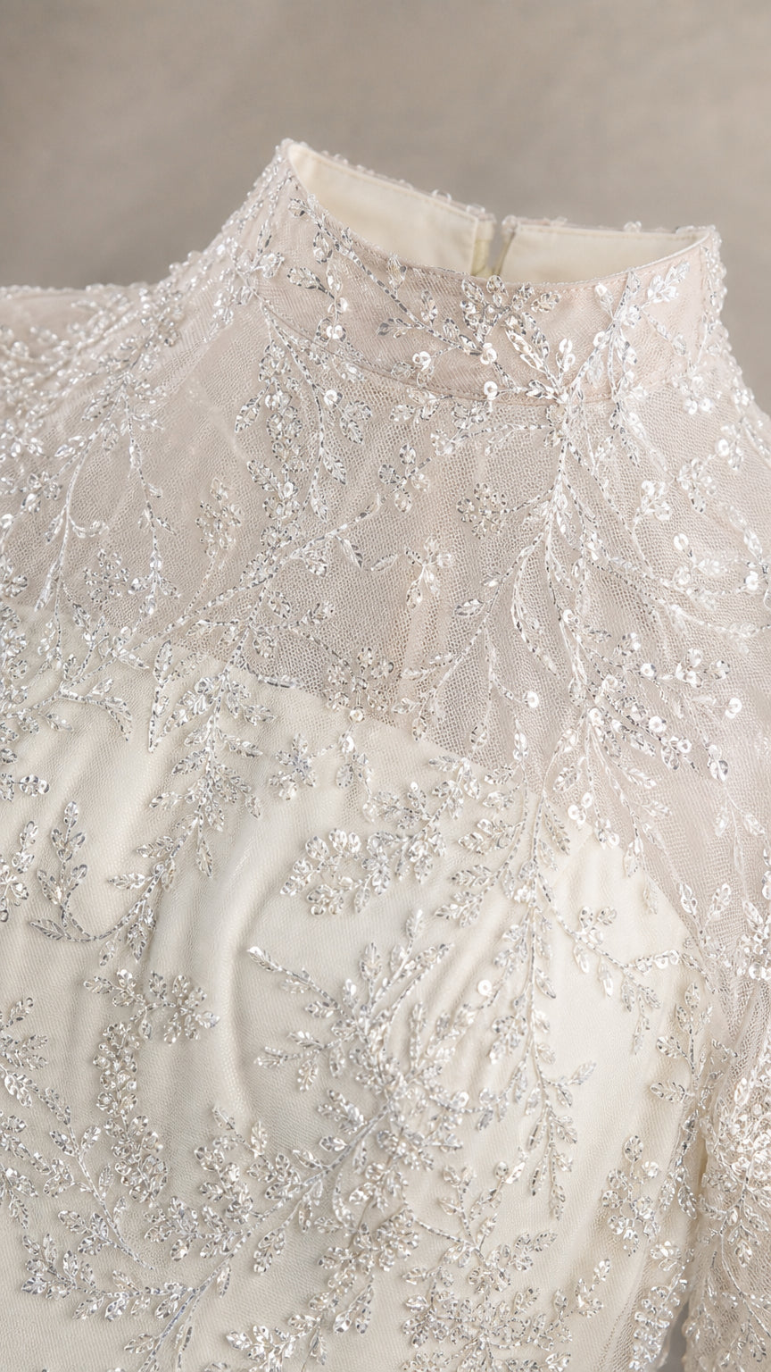 Close-up of delicate sequin embroidery on high mock neckline
