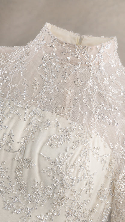 Close-up of delicate sequin embroidery on high mock neckline